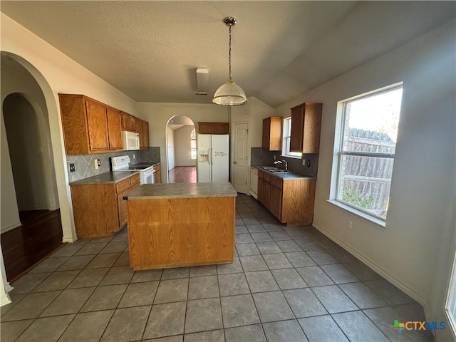 kitchen with a center island, pendant lighting, white appliances, decorative backsplash, and light tile patterned floors