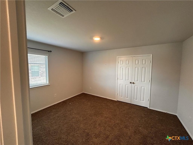 unfurnished bedroom featuring dark colored carpet and a closet