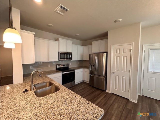 kitchen featuring light stone countertops, appliances with stainless steel finishes, sink, pendant lighting, and dark hardwood / wood-style floors