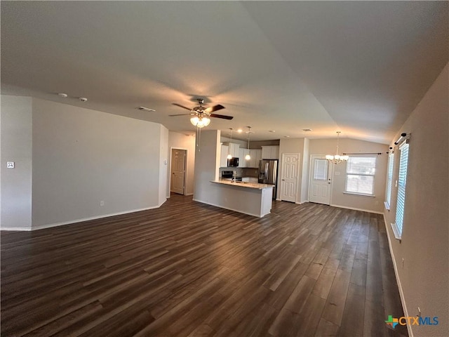 unfurnished living room with ceiling fan with notable chandelier, lofted ceiling, and dark wood-type flooring