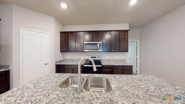 kitchen with dark brown cabinetry, light stone counters, sink, and stainless steel appliances