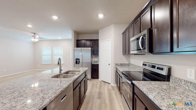 kitchen featuring light stone countertops, appliances with stainless steel finishes, ceiling fan, sink, and light hardwood / wood-style floors