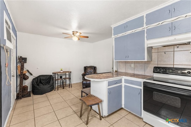 kitchen with light tile patterned floors, blue cabinetry, backsplash, range with electric stovetop, and kitchen peninsula