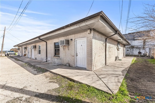 view of property exterior with an AC wall unit and a patio area