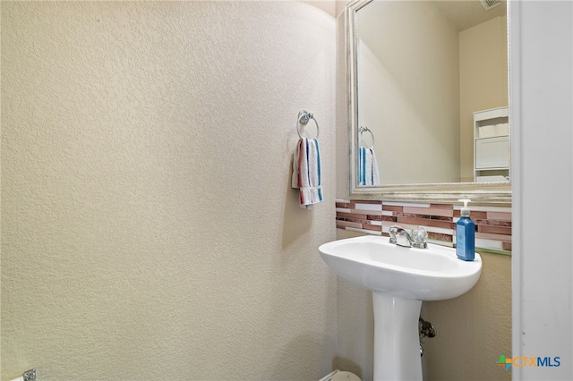 326 Comal Run, Hutto, TX 78634 - bathroom with tasteful backsplash and a textured wall