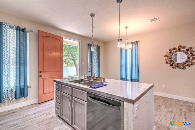 kitchen with a center island with sink, dishwasher, a textured ceiling, pendant lighting, and sink