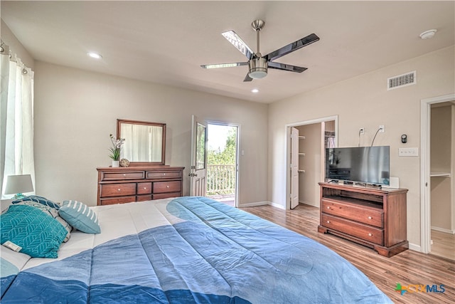 bedroom with ceiling fan, a walk in closet, light hardwood / wood-style floors, and access to outside