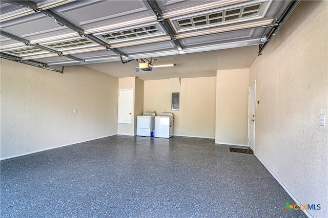 garage featuring electric panel, a garage door opener, and washing machine and clothes dryer