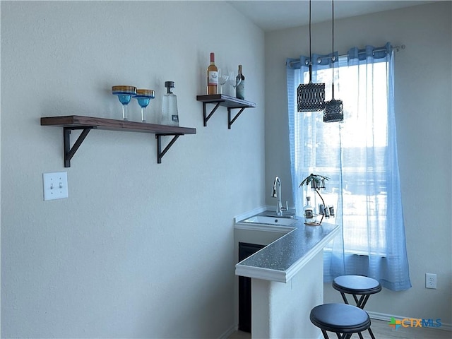 bar featuring hanging light fixtures and sink