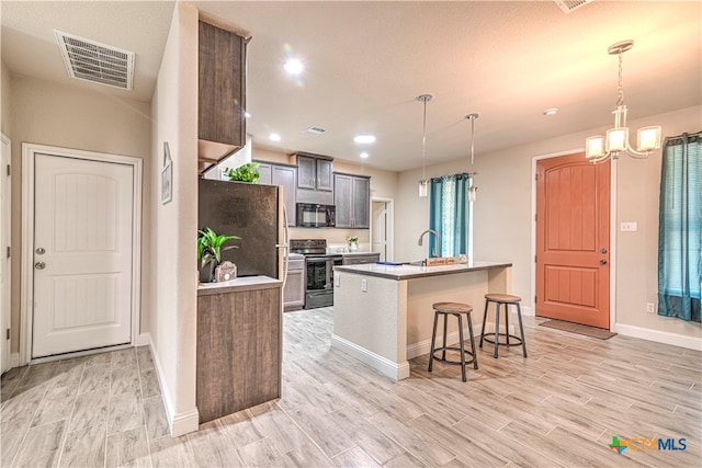 kitchen featuring black appliances, a kitchen island with sink, hanging light fixtures, and dark brown cabinetry