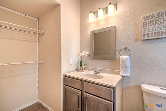 bathroom with toilet, hardwood / wood-style flooring, and vanity