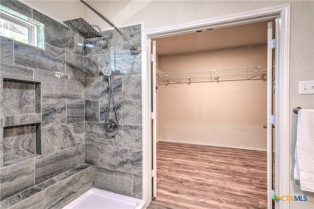 bathroom featuring wood-type flooring and a tile shower