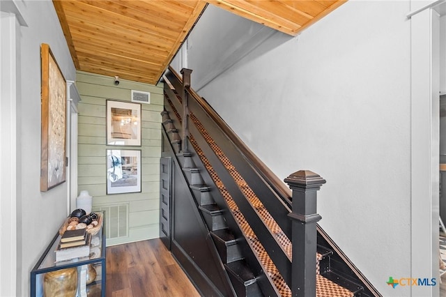 stairs featuring wood-type flooring, wood ceiling, and wood walls