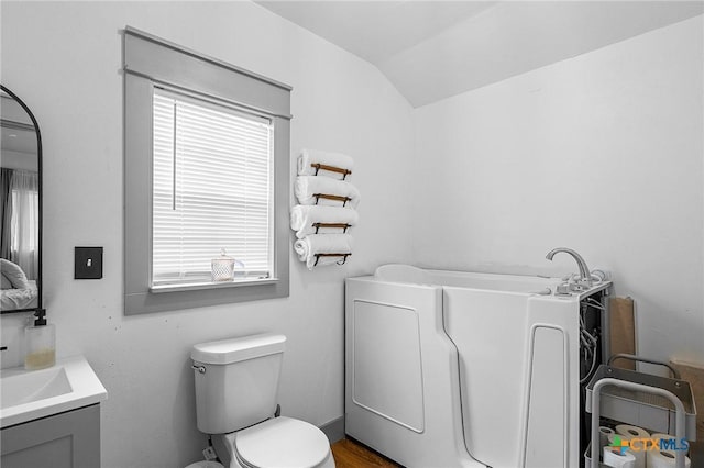 bathroom featuring washer / dryer, vanity, lofted ceiling, and toilet