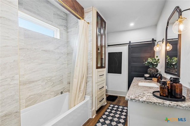 bathroom featuring hardwood / wood-style flooring, vanity, and shower / tub combo