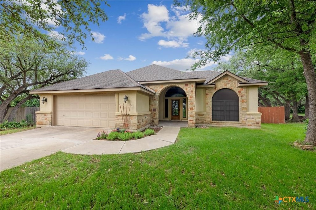 ranch-style home with stucco siding, driveway, fence, a front yard, and an attached garage