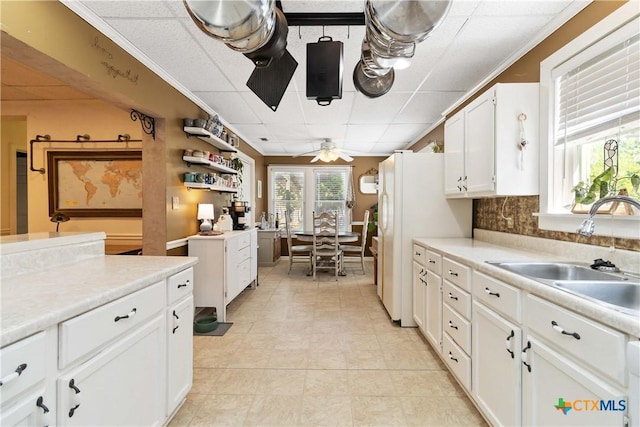 859 Pine St, New Braunfels, TX 78130 - kitchen featuring a sink, ceiling fan, light tile patterned floors, light countertops, and white cabinetry