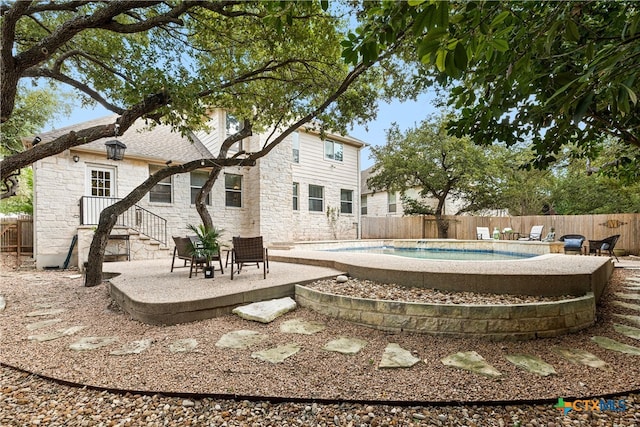 rear view of property featuring a fenced in pool and a patio area