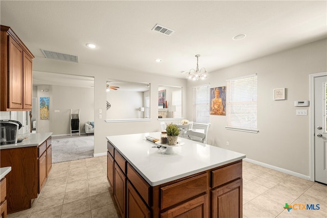 kitchen featuring ceiling fan with notable chandelier, light tile patterned floors, decorative light fixtures, and a center island