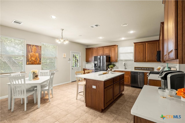 kitchen featuring an inviting chandelier, sink, a kitchen island with sink, pendant lighting, and appliances with stainless steel finishes