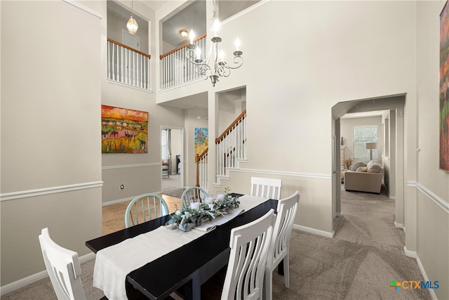 carpeted dining room with a high ceiling and a notable chandelier