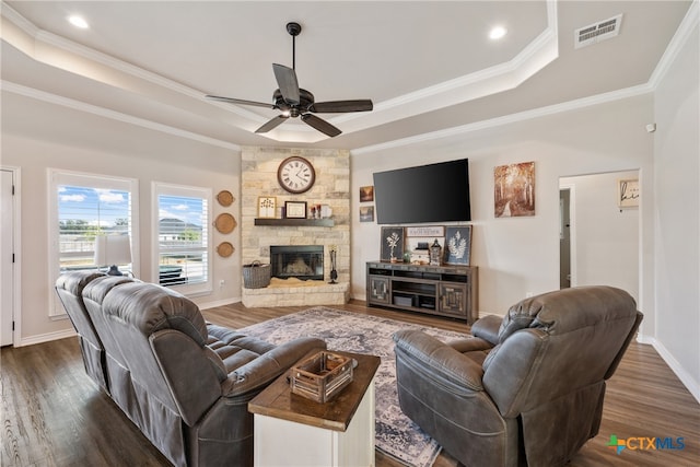 living room with ceiling fan, a raised ceiling, dark hardwood / wood-style flooring, and ornamental molding