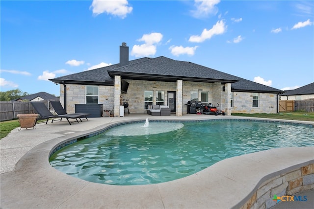 view of pool with grilling area, pool water feature, and a patio area