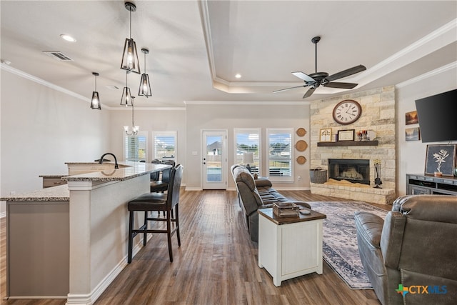 living room featuring ornamental molding, a fireplace, ceiling fan with notable chandelier, and dark hardwood / wood-style floors