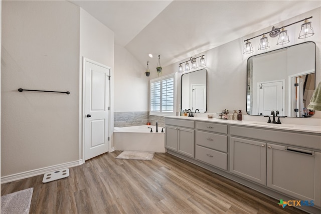 bathroom featuring a washtub, lofted ceiling, hardwood / wood-style flooring, and vanity