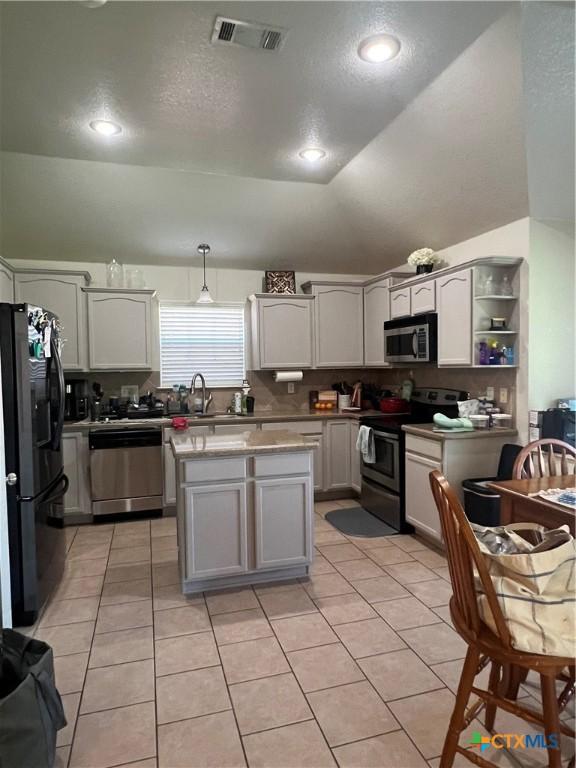 2019 Stonehenge Dr, Harker Heights, TX 76548 - kitchen featuring appliances with stainless steel finishes, light tile patterned floors, a sink, lofted ceiling, and a kitchen island