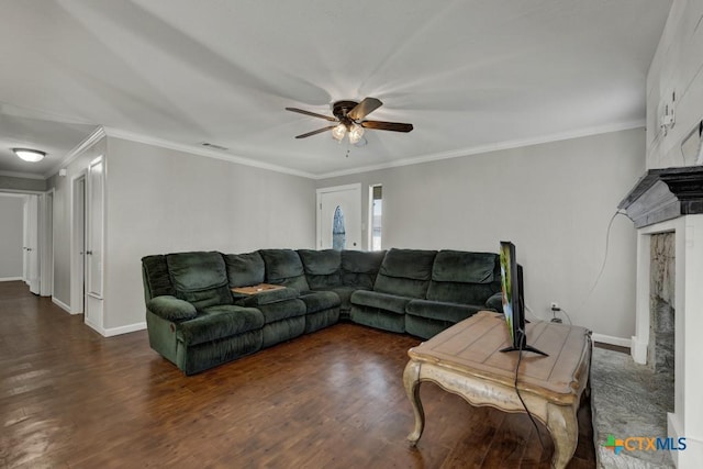 living room with dark hardwood / wood-style floors, ornamental molding, a large fireplace, and ceiling fan