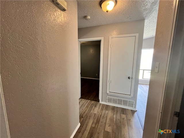 corridor featuring a textured ceiling and hardwood / wood-style flooring