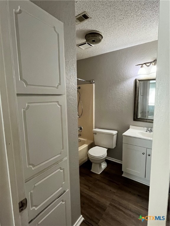 full bathroom featuring bathing tub / shower combination, a textured ceiling, toilet, vanity, and hardwood / wood-style flooring