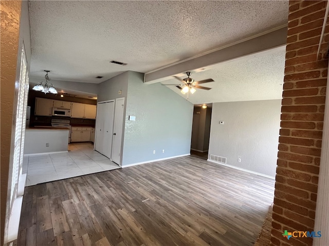 unfurnished living room with lofted ceiling with beams, light hardwood / wood-style floors, and a textured ceiling