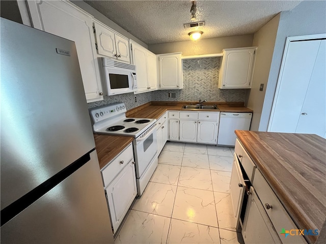 kitchen with butcher block counters, white cabinetry, white appliances, and decorative backsplash