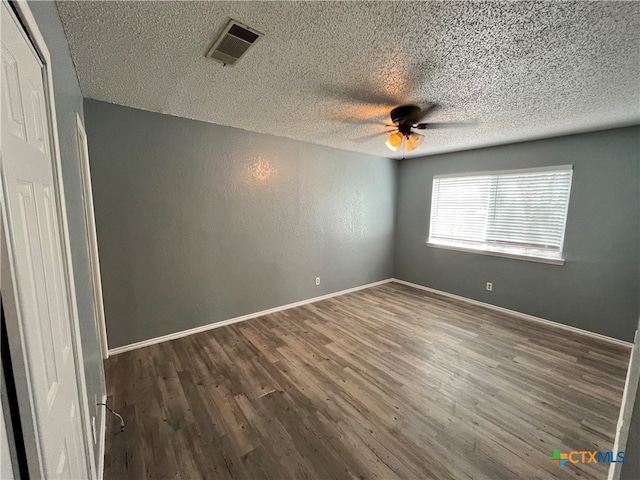 spare room featuring dark hardwood / wood-style floors, ceiling fan, and a textured ceiling