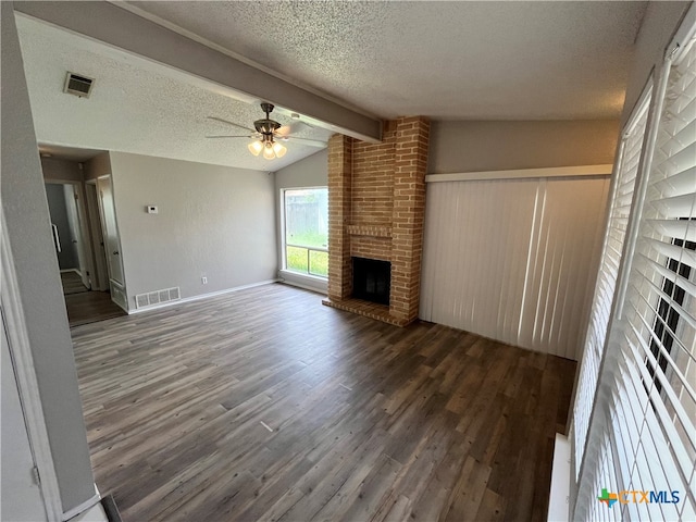 unfurnished living room with ceiling fan, a brick fireplace, vaulted ceiling with beams, dark hardwood / wood-style flooring, and a textured ceiling