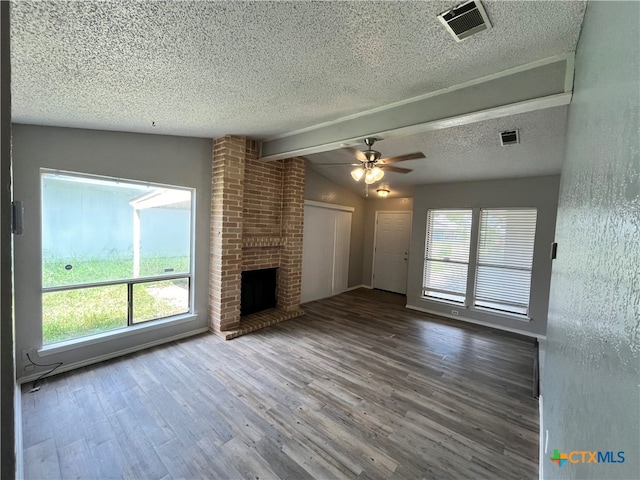 unfurnished living room with a fireplace, hardwood / wood-style floors, vaulted ceiling with beams, and plenty of natural light