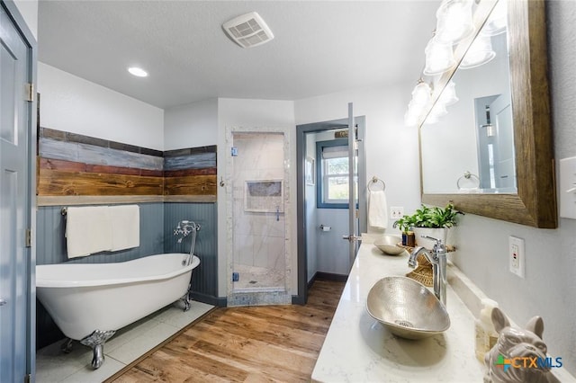 full bathroom featuring visible vents, a soaking tub, wood finished floors, a shower stall, and a sink