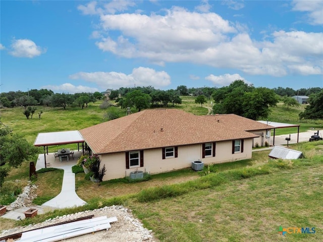 back of house featuring central AC, a lawn, and roof with shingles