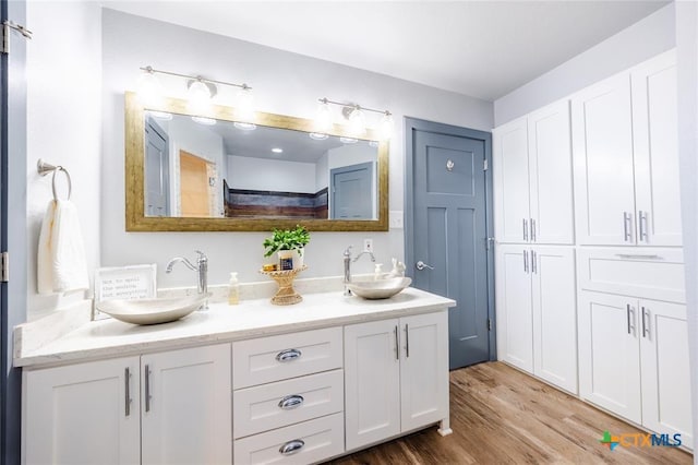 full bathroom featuring double vanity, a sink, and wood finished floors