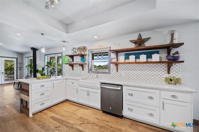 kitchen with open shelves, light wood-style flooring, a sink, dishwasher, and a peninsula