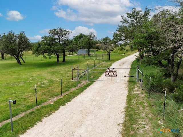 view of home's community featuring driveway, a gate, fence, and a lawn