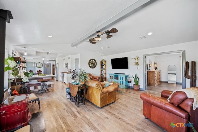 living room featuring lofted ceiling with beams, visible vents, baseboards, a ceiling fan, and light wood-type flooring