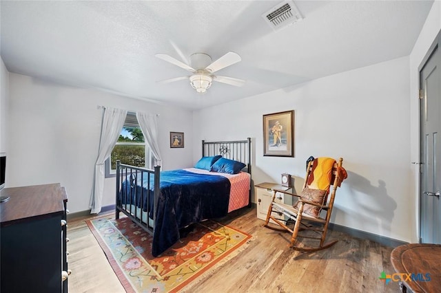 bedroom featuring ceiling fan, light wood-type flooring, visible vents, and baseboards