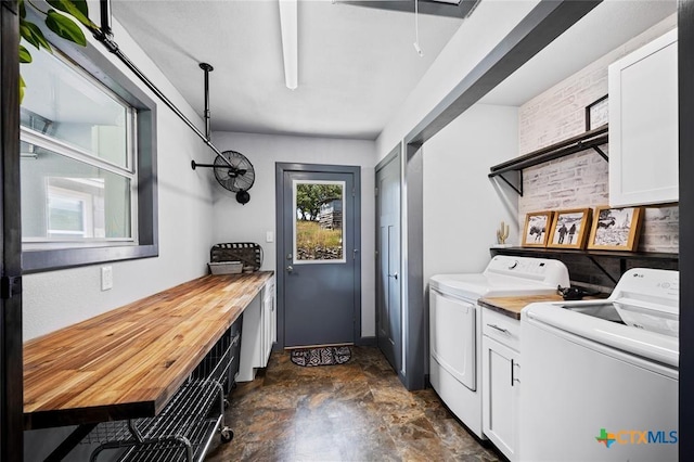 laundry area featuring washing machine and dryer, brick wall, cabinet space, stone finish floor, and attic access