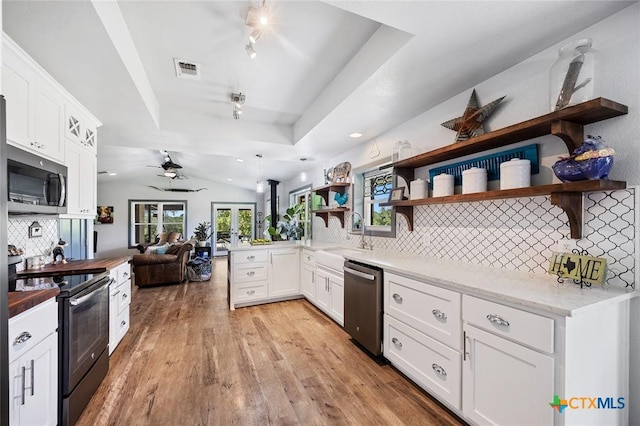 kitchen with appliances with stainless steel finishes, a tray ceiling, light wood-type flooring, open shelves, and a sink