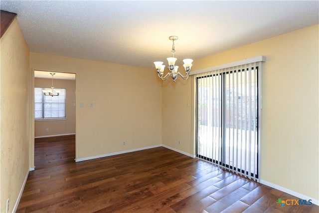 unfurnished room with dark wood-style flooring, a textured ceiling, baseboards, and an inviting chandelier