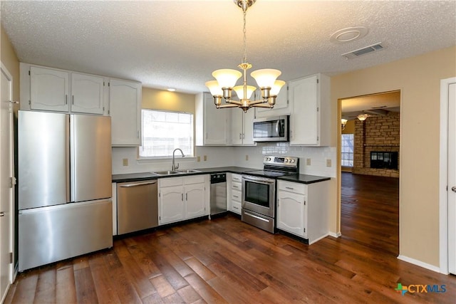 2505 Canyon Creek Dr, Temple, TX 76502 - kitchen featuring stainless steel appliances, a sink, dark countertops, a chandelier, and white cabinetry