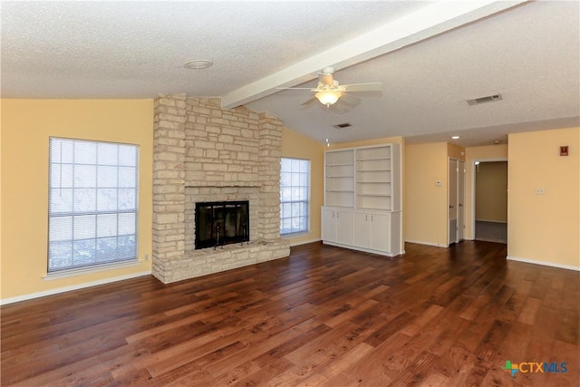 unfurnished living room featuring lofted ceiling with beams, a textured ceiling, a stone fireplace, dark wood-type flooring, and visible vents